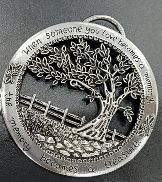 Silver tree ornament with engraved text on a dark background