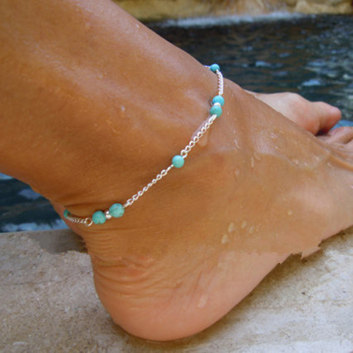 Ankle with turquoise beaded anklet by a pool
