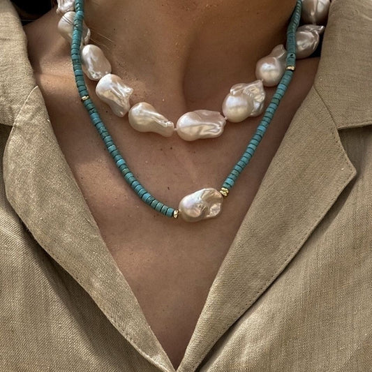 Necklace with pearls and turquoise beads worn by a person in a beige outfit.