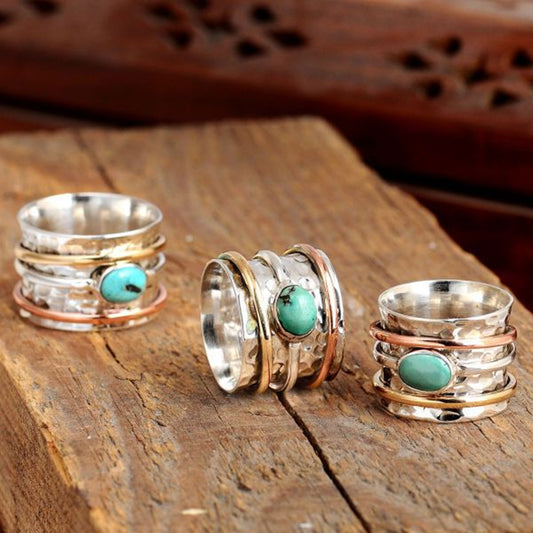 Set of silver and gold rings with turquoise stones on a wooden surface