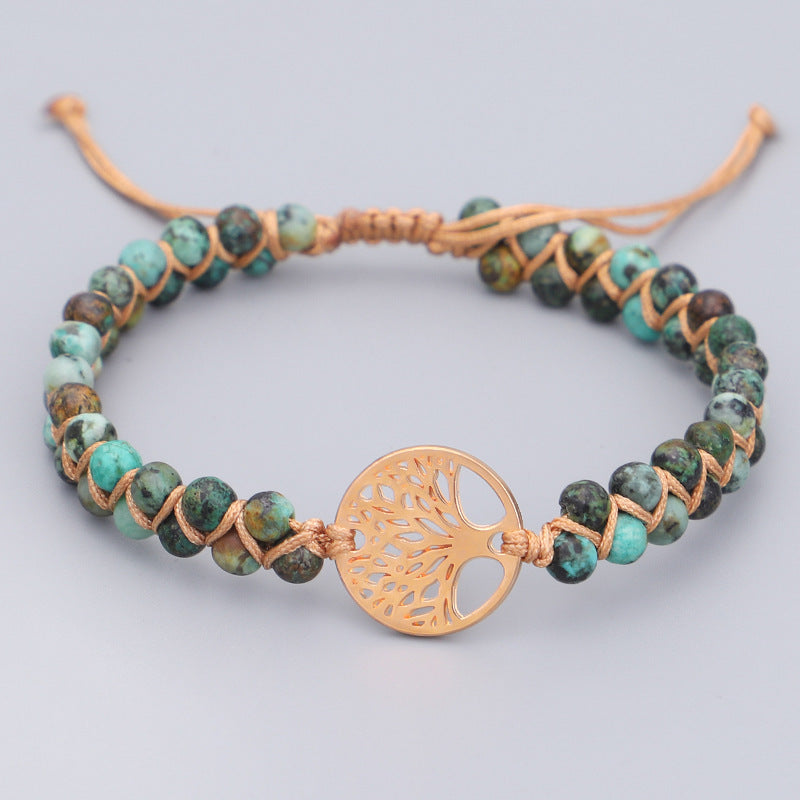 Bracelet with green beads and a gold tree-shaped clasp on a light gray background