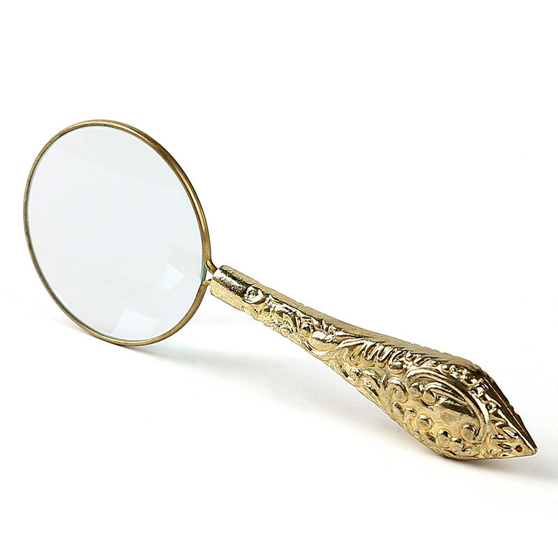 Decorative gold magnifying glass on a white background