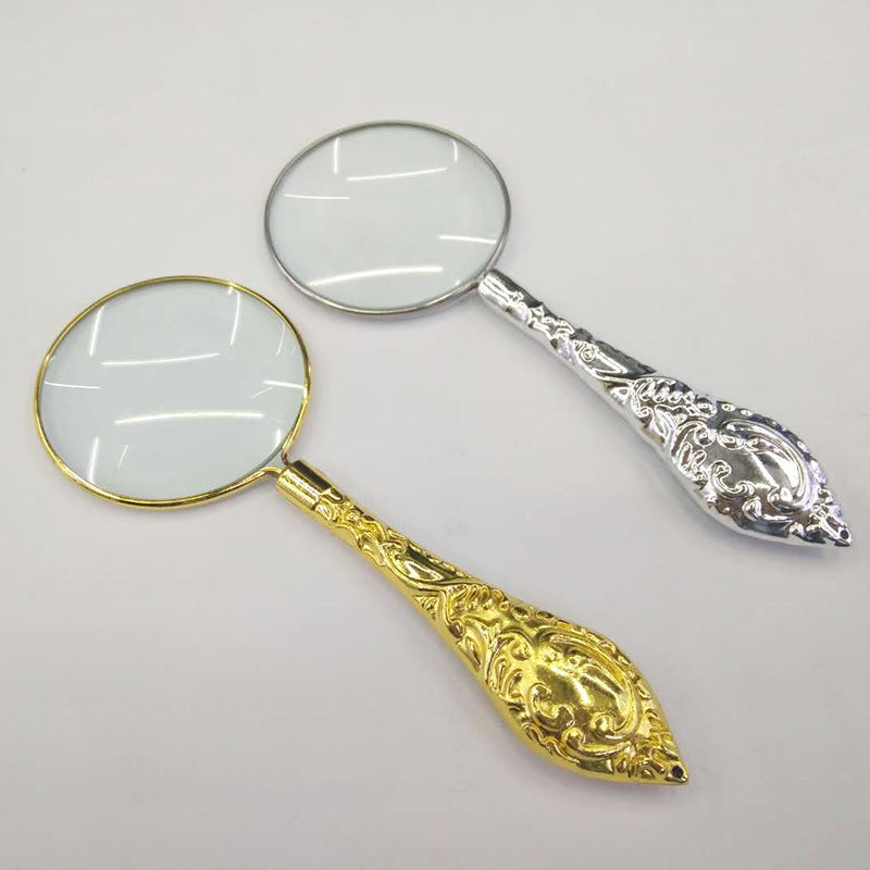 Two ornate magnifying glasses, one gold and one silver, on a light gray background.