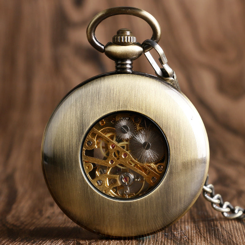 Vintage pocket watch with visible mechanical components on a wooden surface