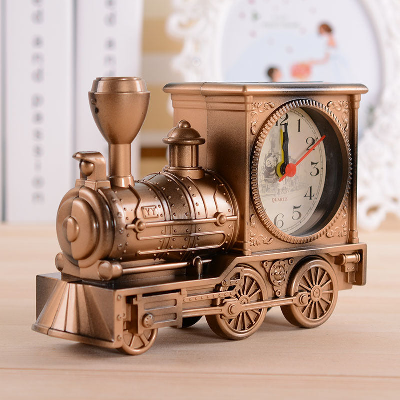Bronze-colored train-shaped clock on a wooden surface with a blurred background