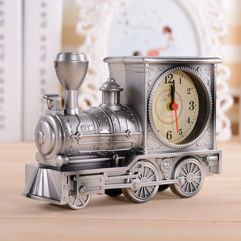 Vintage-style train clock on a wooden surface with a blurred decorative background