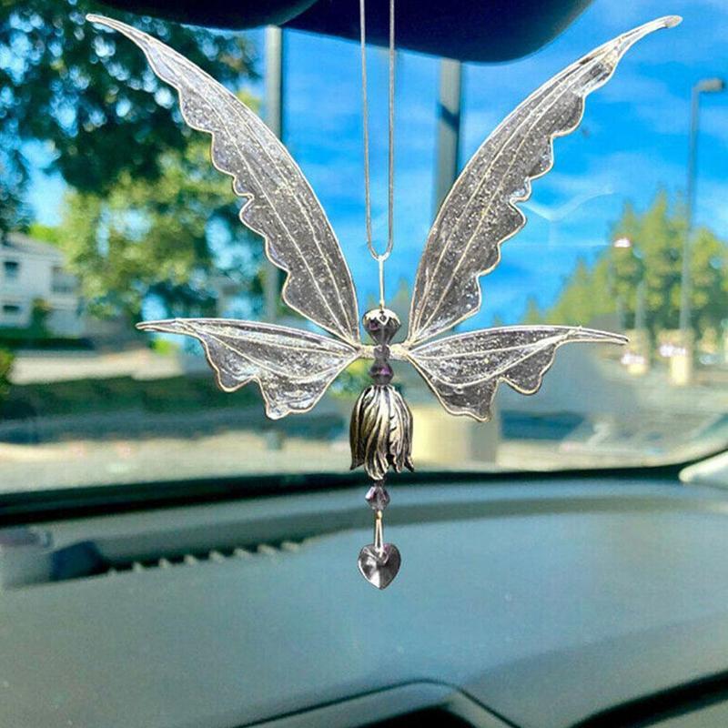 Decorative butterfly car hanging on a car's rearview mirror with a blurred outdoor background.