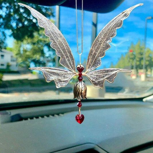 Decorative butterfly-shaped car hanging with red heart on a car dashboard.
