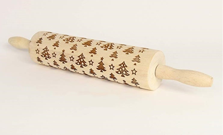 Wooden rolling pin with Christmas tree and star patterns on a white background