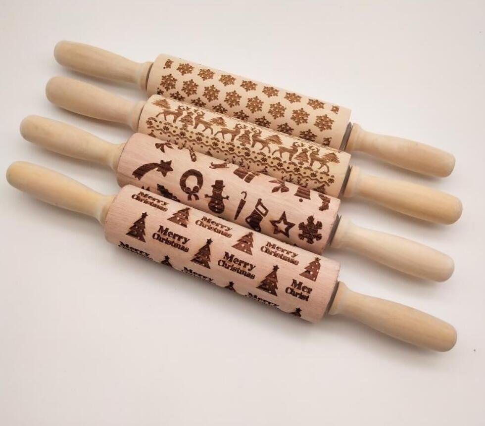 Four wooden rolling pins with embossed Christmas designs on a white background
