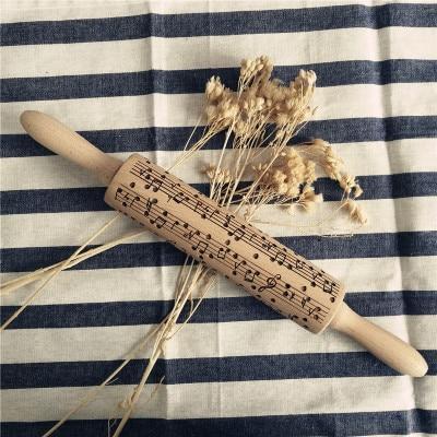 Wooden rolling pin with musical notes on a striped fabric background