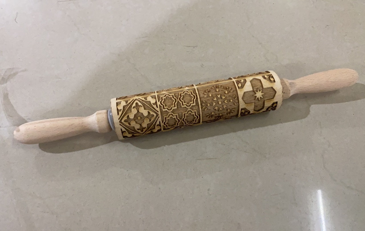 Decorative rolling pin with embossed patterns on a light gray surface