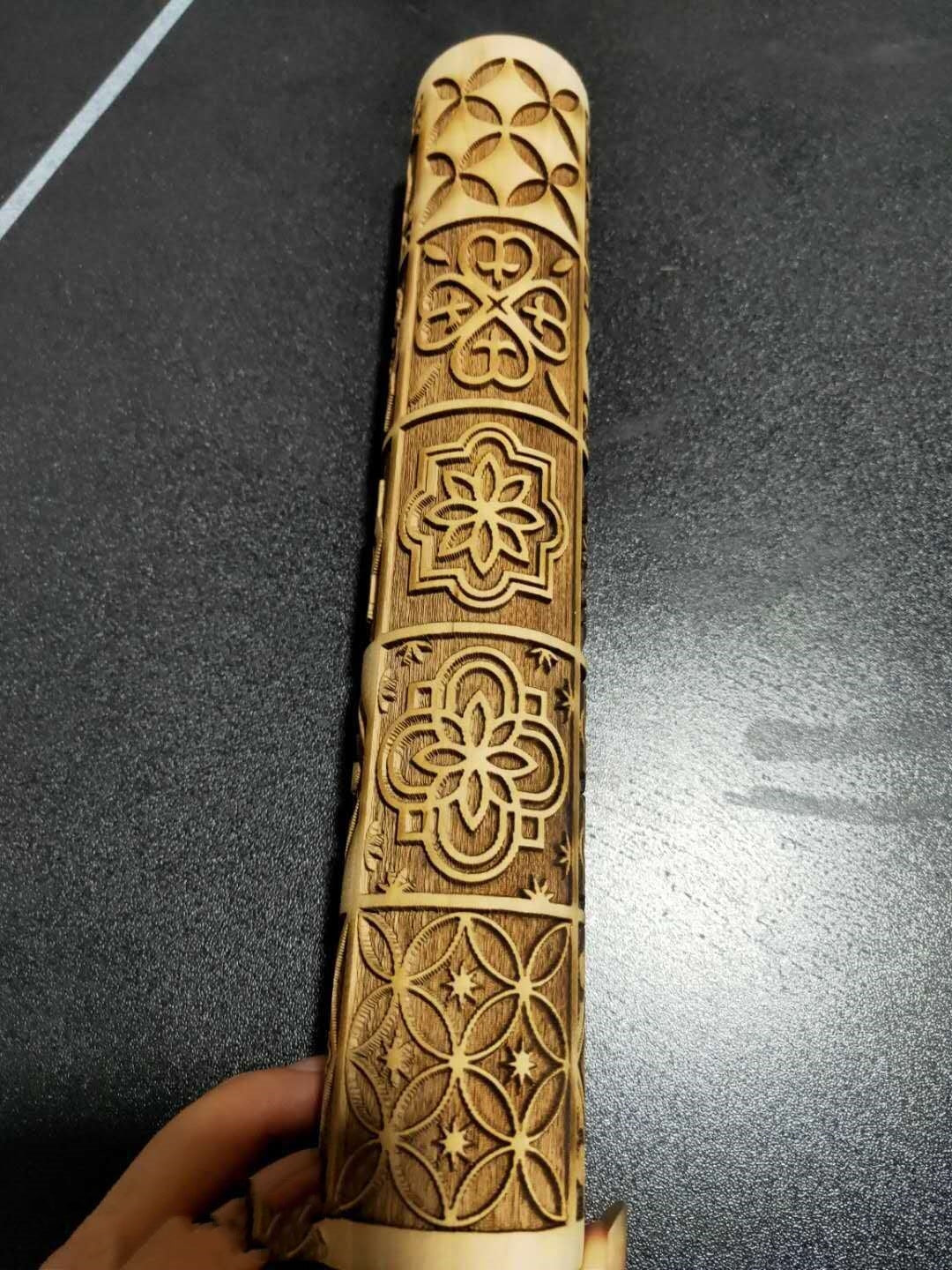 Wooden handle with intricate laser-cut patterns on a dark surface