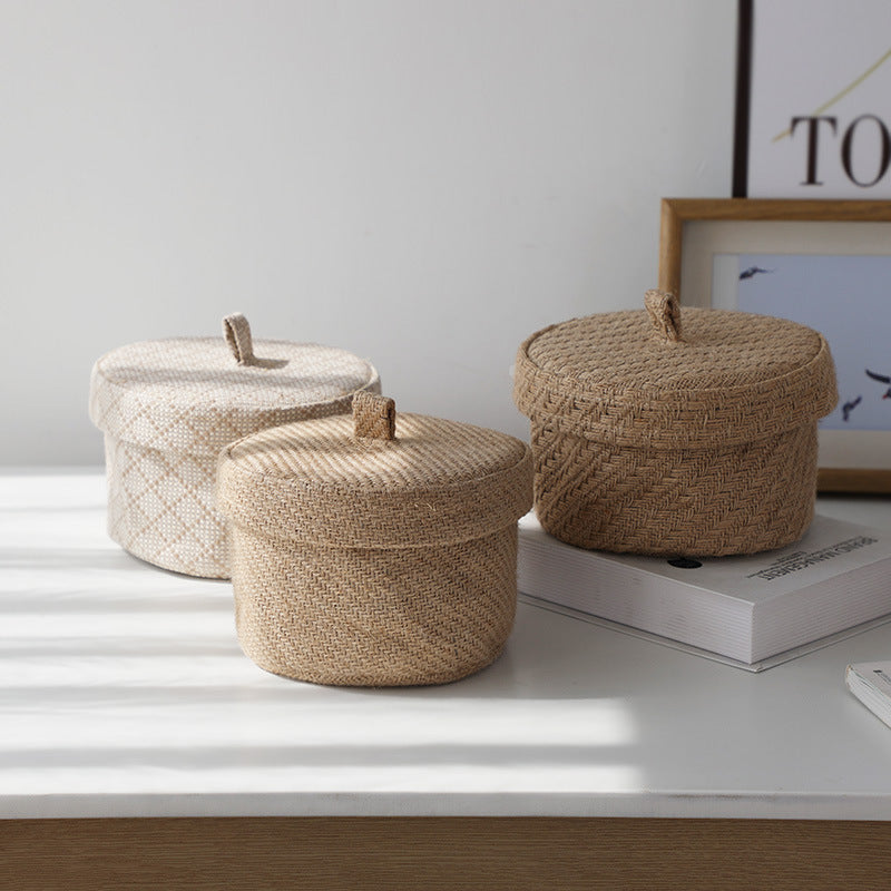Three woven baskets with lids on a white surface.