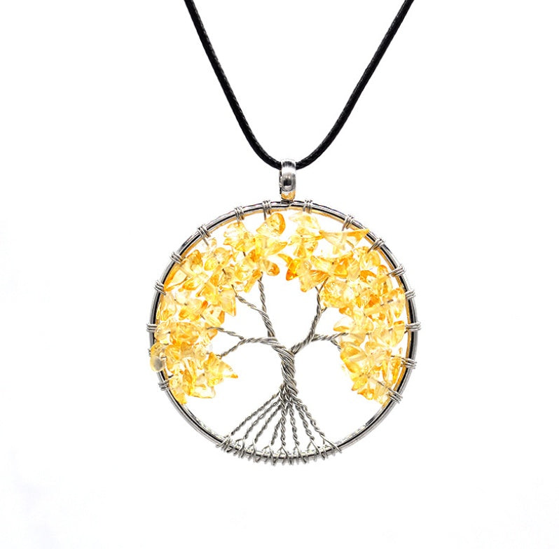 Tree-shaped pendant with yellow stones on a black cord against a white background