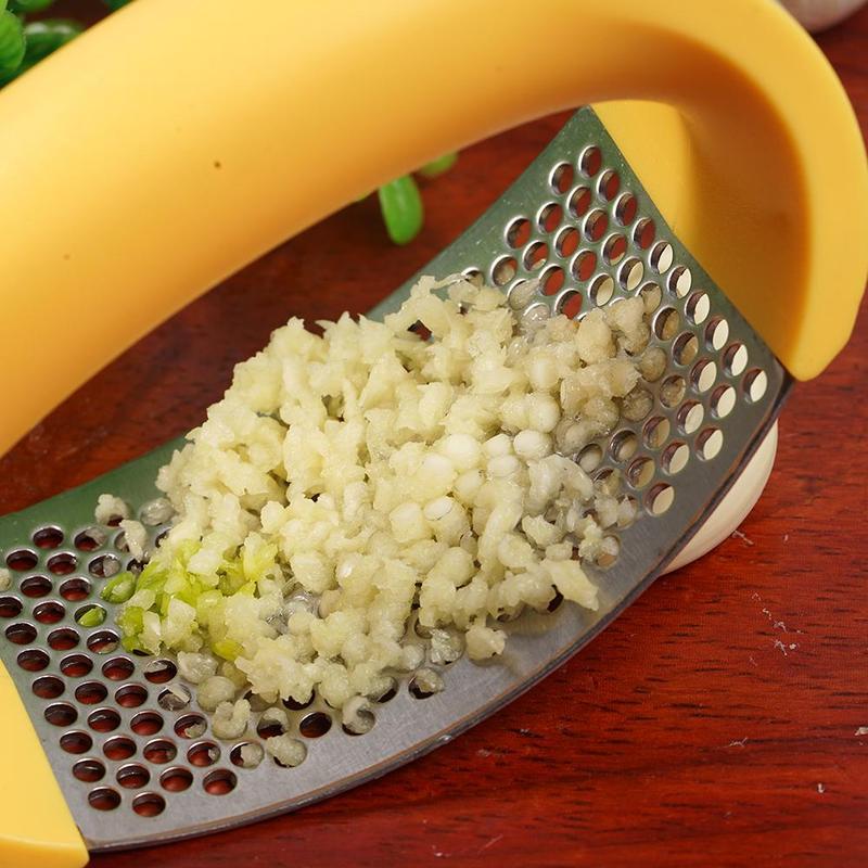 Yellow handheld grater with grated white vegetable on a wooden surface