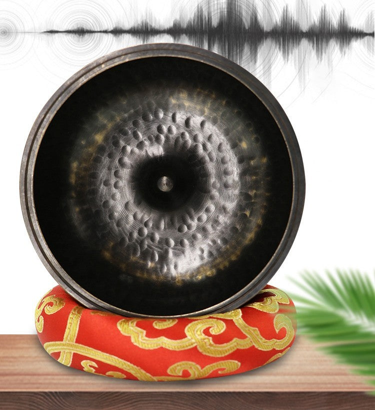 Decorative gong on a red and gold cushion with a white background