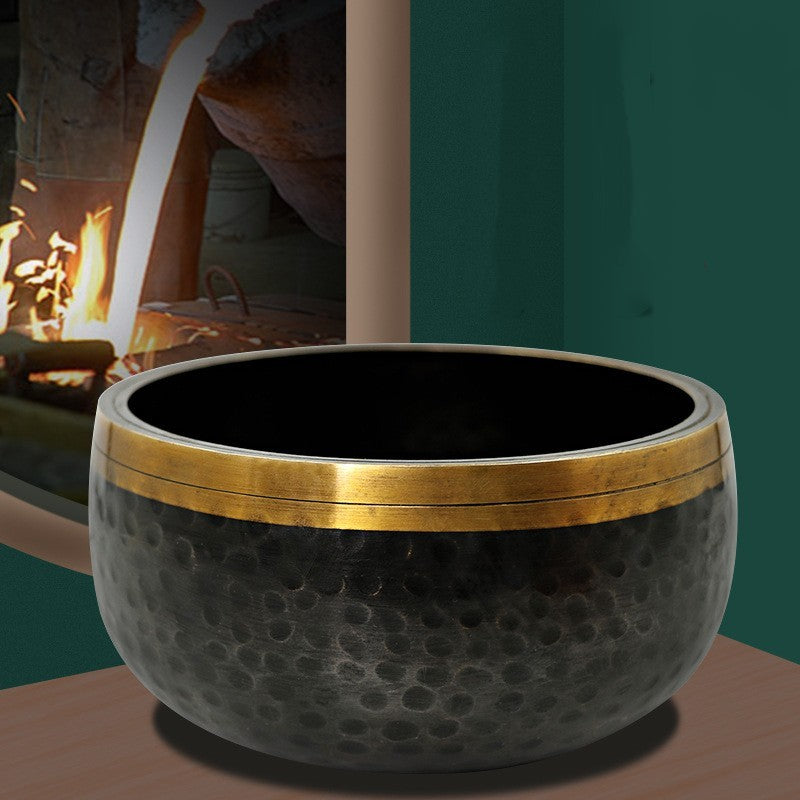 Decorative black and gold bowl on a table with a blurred background