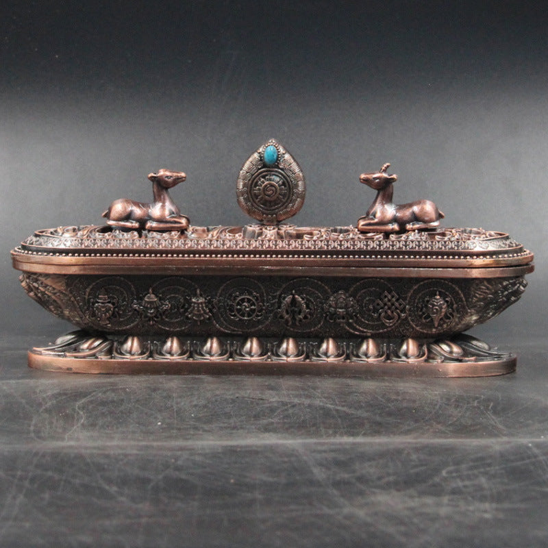 Decorative bronze incense burner with two dogs and a central emblem on a dark gray background