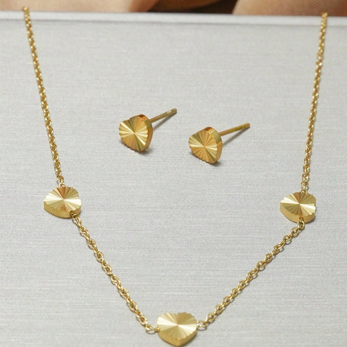 Gold necklace and earrings on a light gray background