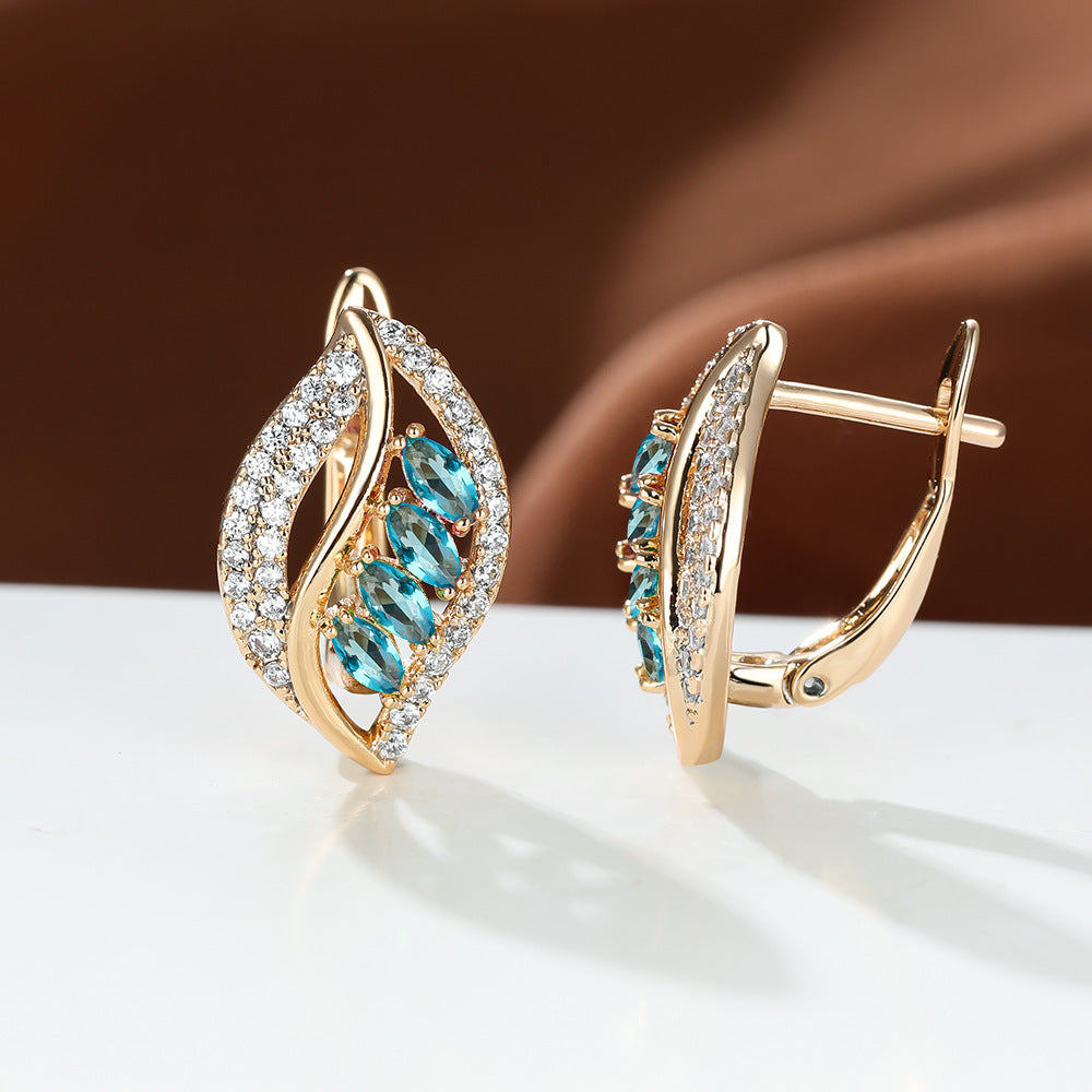 Gold earrings with blue gemstones on a white surface with a brown background
