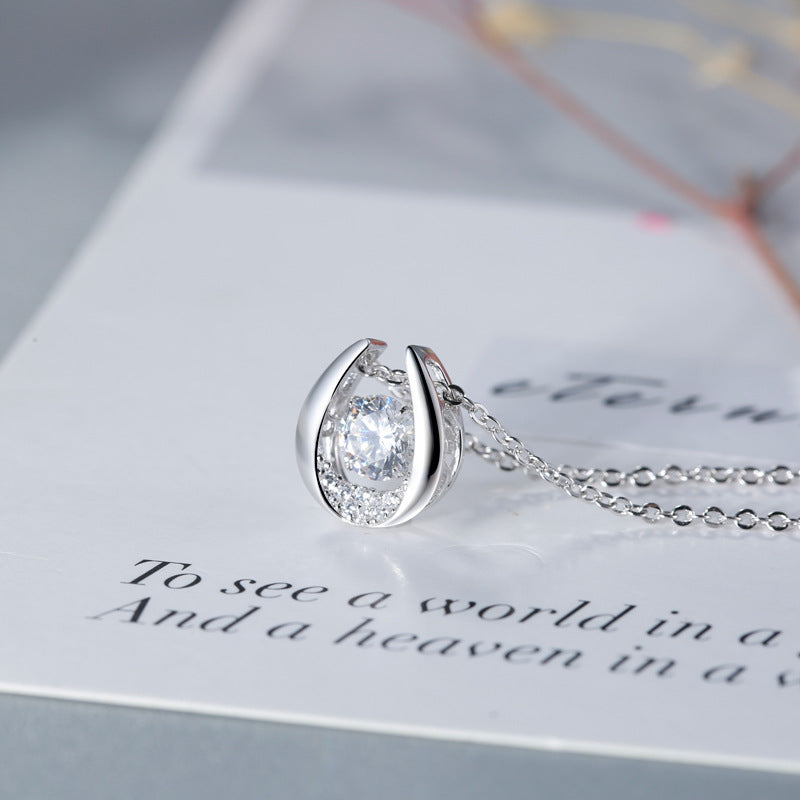 Silver teardrop-shaped necklace with a clear gemstone on a decorative card.