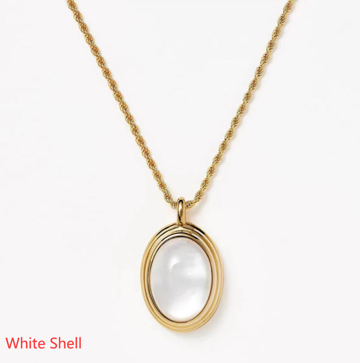 Gold necklace with a white shell pendant on a white background