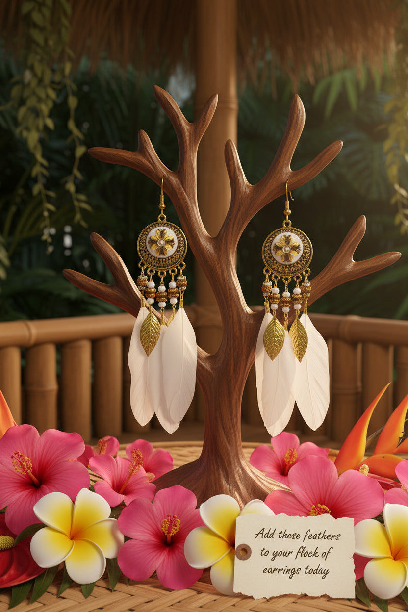 Pair of gold and white feathered earrings on a green patterned background