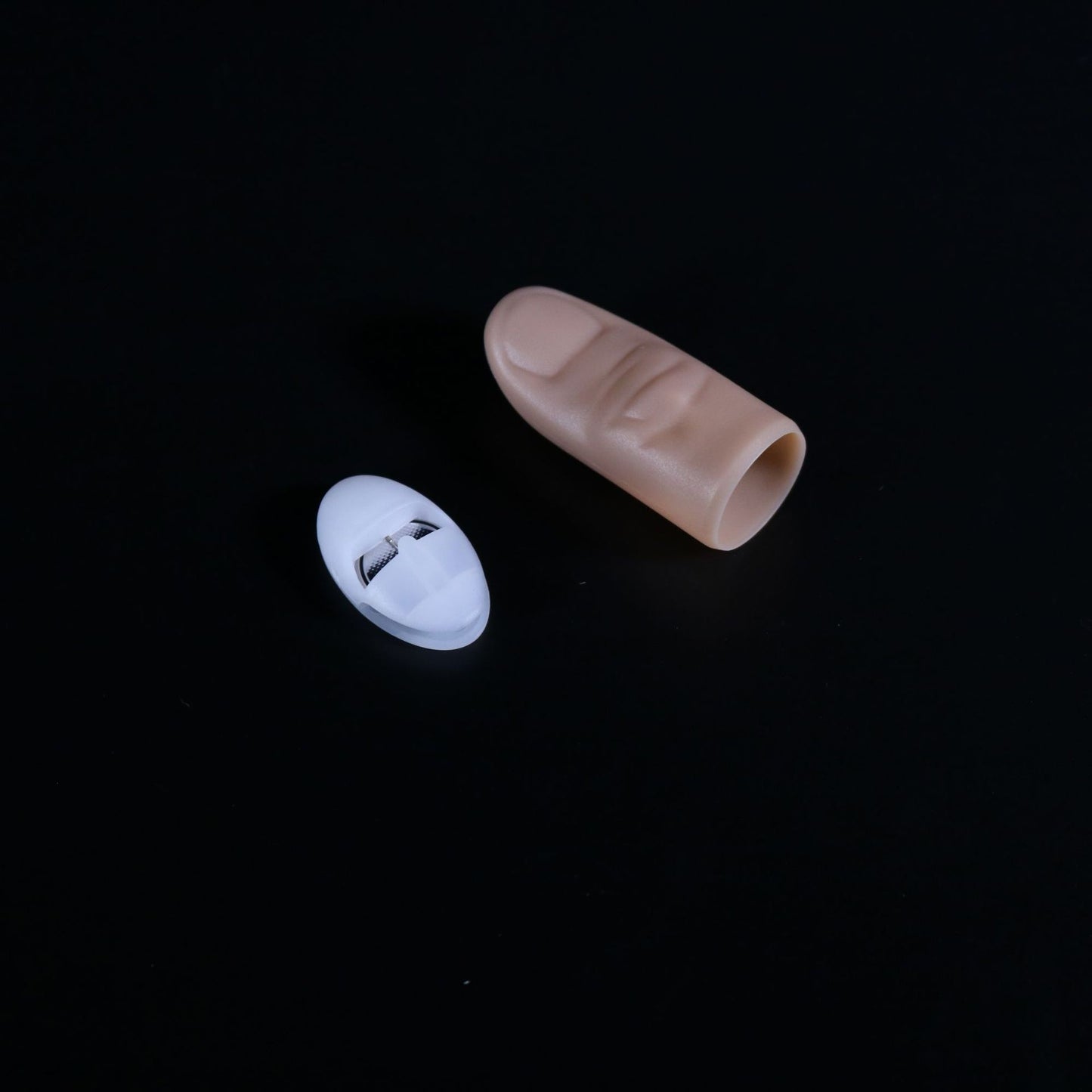 Beige finger sleeve and white cap on a black background