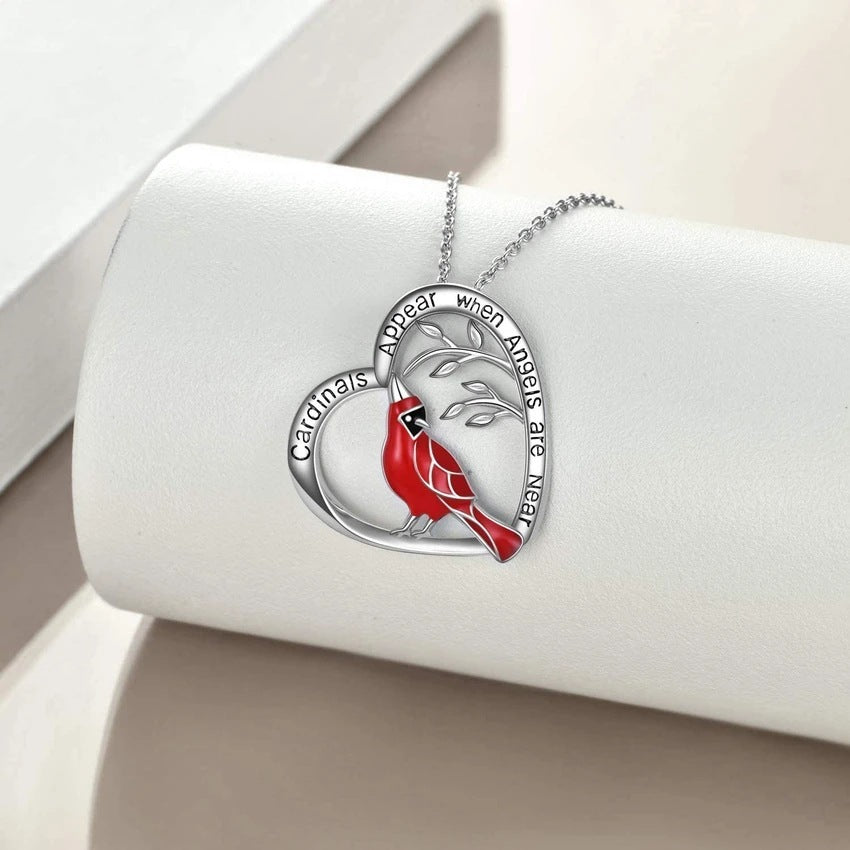 Heart-shaped pendant with a red cardinal design on a white cushion