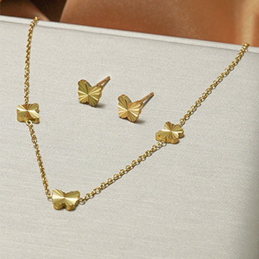 Gold necklace and earrings set on a light gray surface
