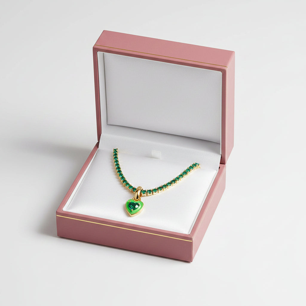 Gold necklace with green gemstone heart pendant on a white background