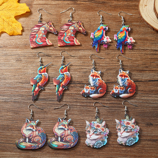 Collection of colorful animal-themed earrings on a wooden surface.