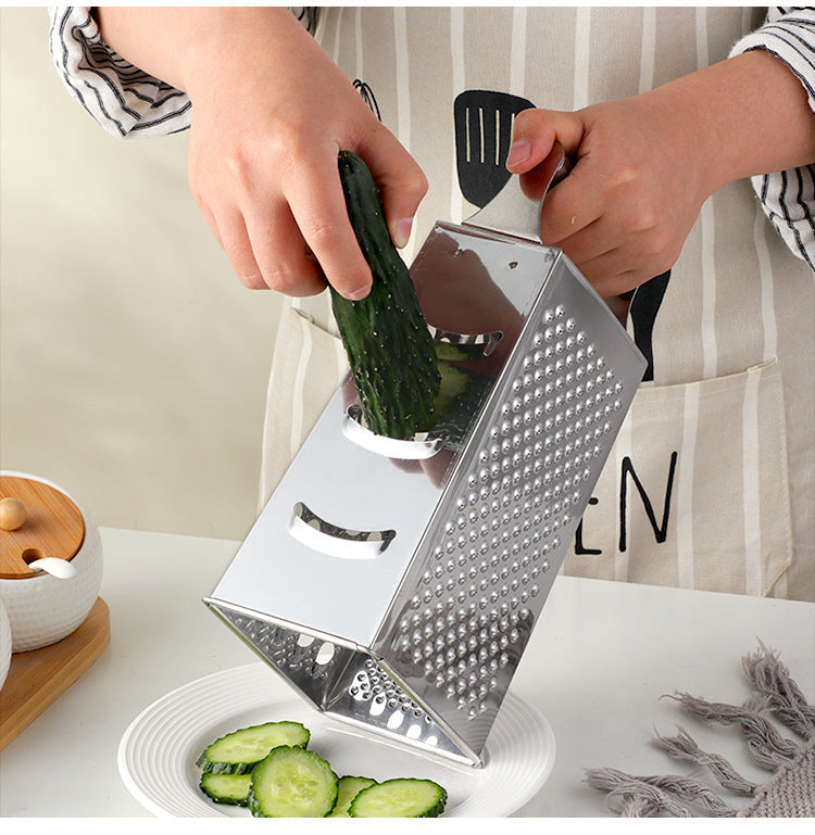 Person using a box grater to slice cucumbers on a kitchen counter.