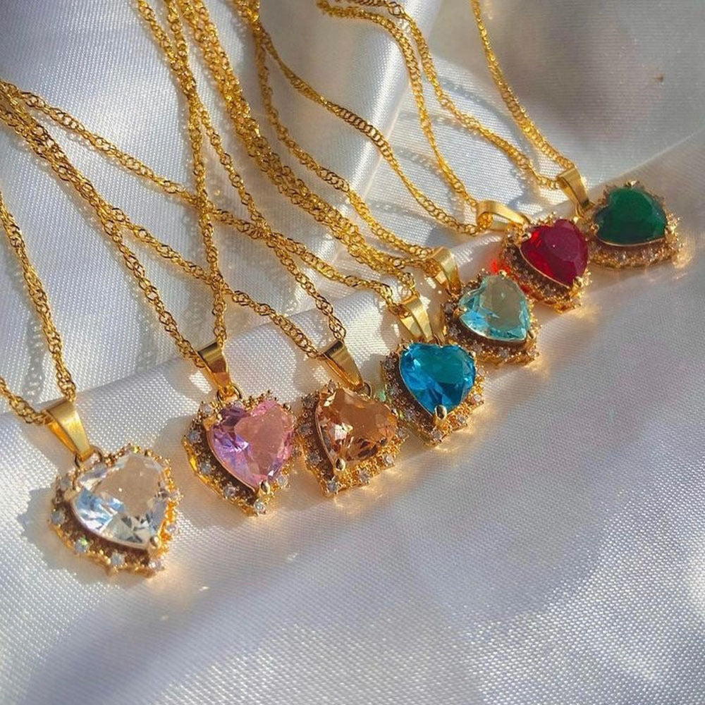 Gold necklaces with heart-shaped gemstones on a white fabric background