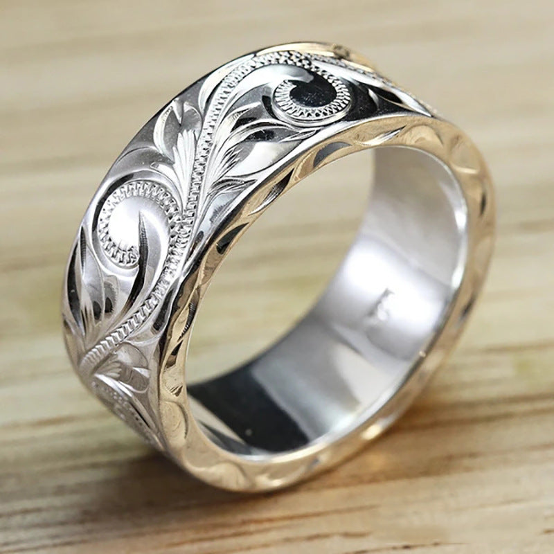 Silver ring with intricate designs on a wooden surface