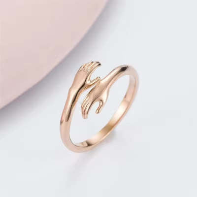 Rose gold hand-shaped ring on a light pink background