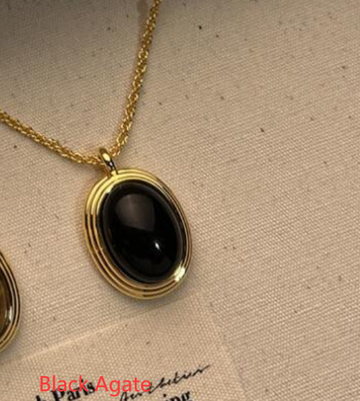 Gold necklace with a black agate pendant on a beige fabric background
