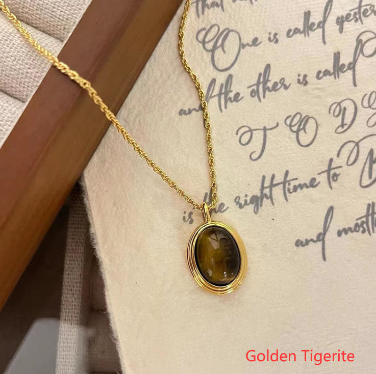 Gold necklace with a tiger eye pendant on a textured surface