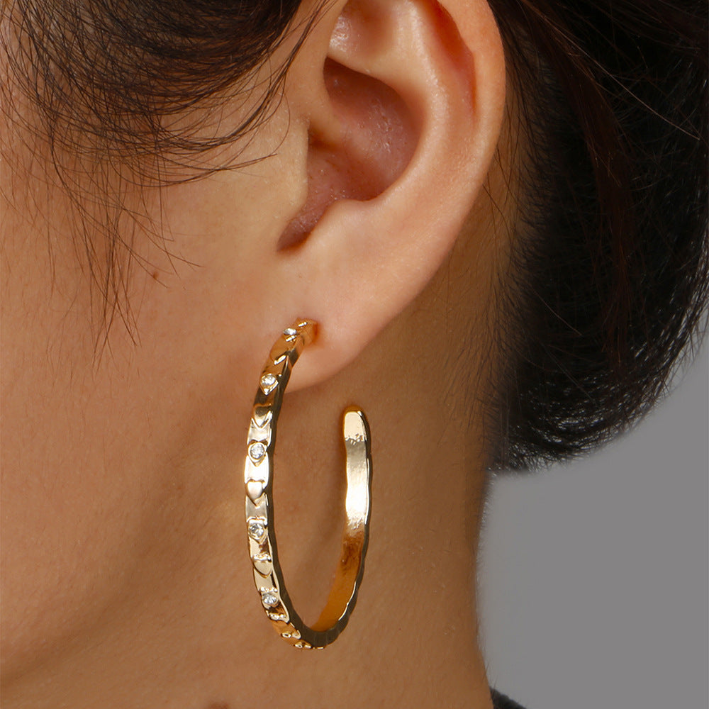 Gold hoop earring worn by a person with a neutral background