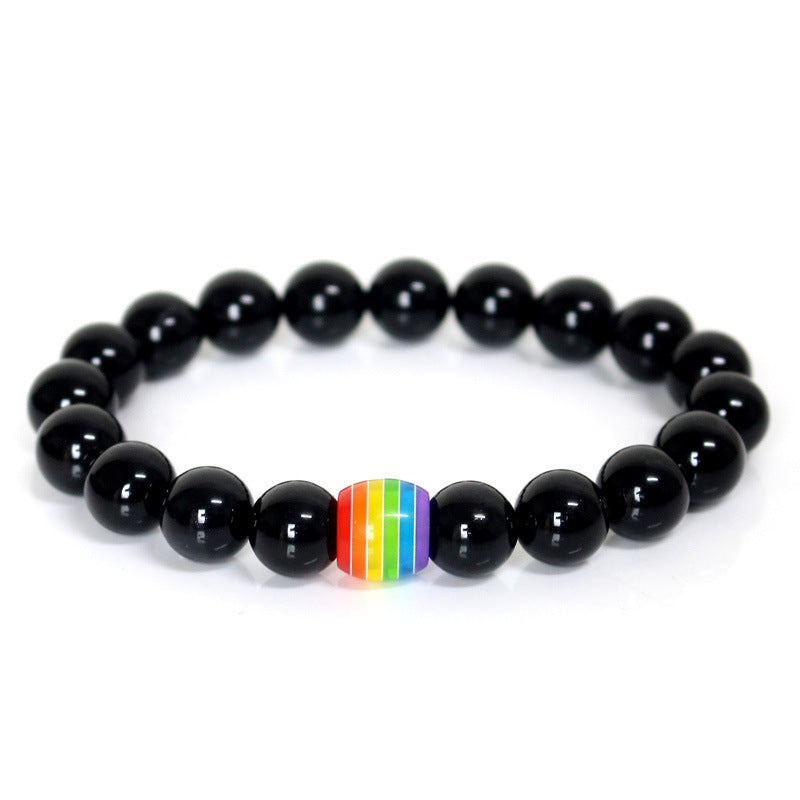 Black beaded bracelet with a rainbow striped charm on a white background