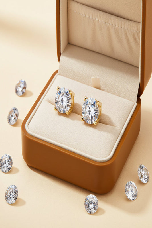 Gold earrings in a gift box with clear gemstones on a table