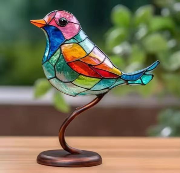 Colorful stained glass bird sculpture on a stand with a blurred green background