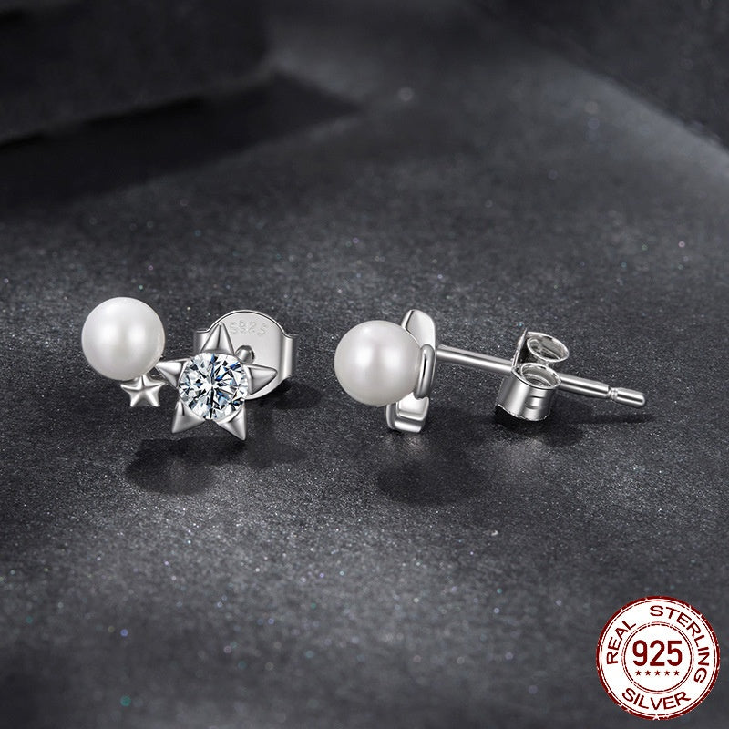 Pair of pearl and star-shaped silver earrings on a dark surface with '925 Sterling Silver' stamp.