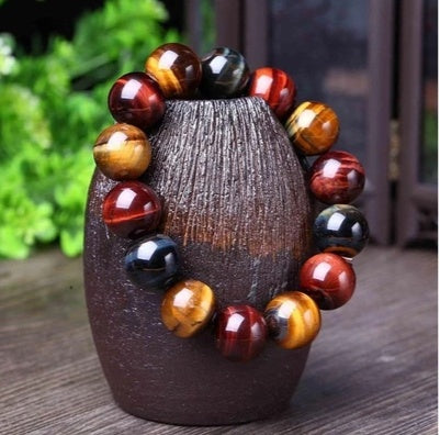 Eye of the tiger beaded bracelet on a textured wooden stand with a blurred green background