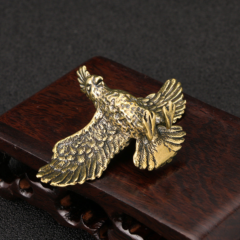 Bronze eagle figurine on a wooden base with a dark background