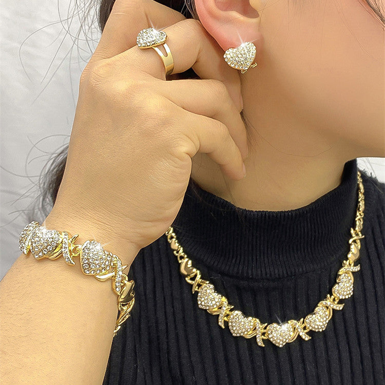 Gold jewelry including necklace, bracelet, and earrings on a person wearing a black top.