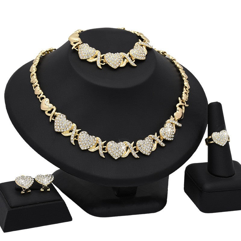 Gold necklace, bracelet, earrings, and ring set on a black stand with a white background