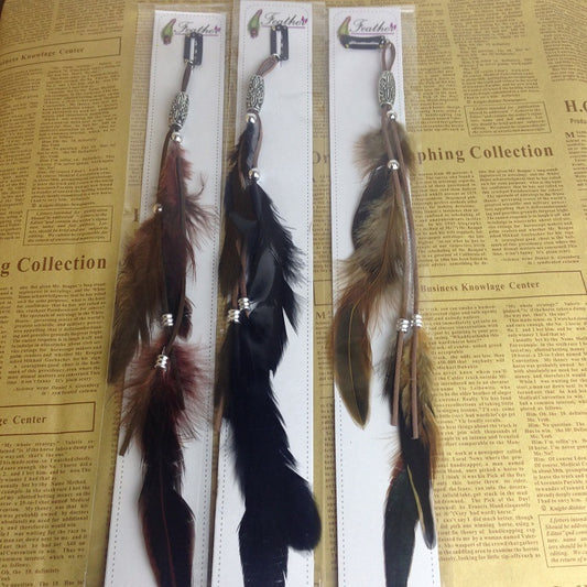 Three feather hair accessories on a ruler with a newspaper background
