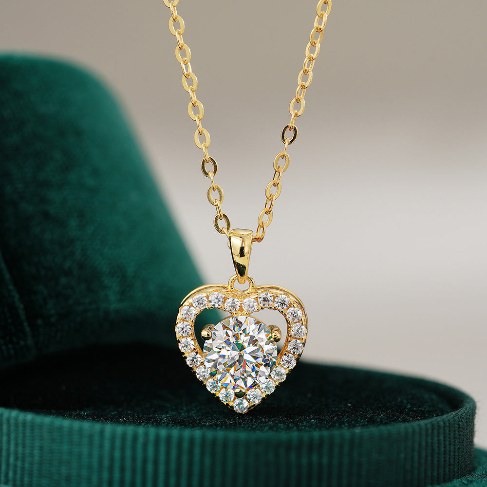 Gold heart-shaped necklace with clear stones on a green velvet surface